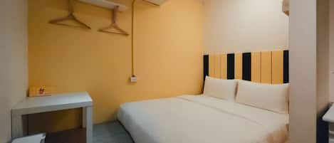 Quarto pequeno e bem arrumado, com cama, mesa de cabeceira e luminária suspensa.