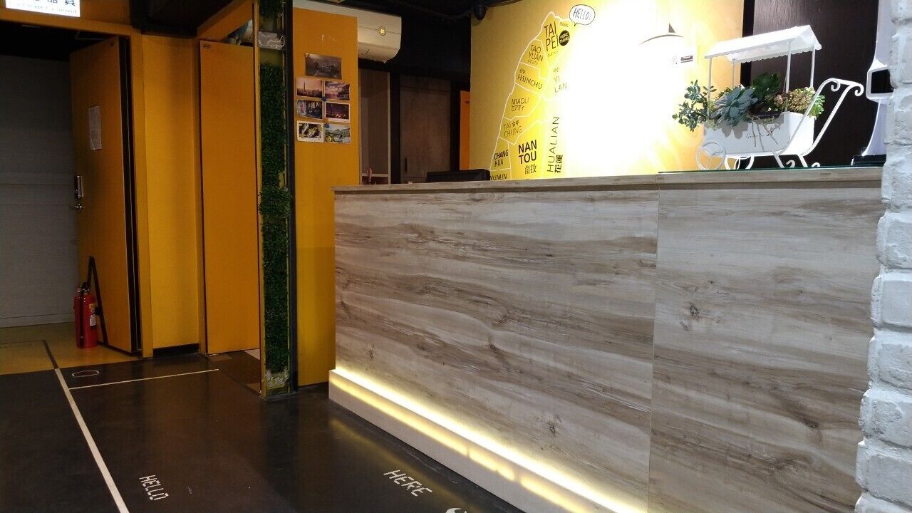 Zona de recepción con un mostrador de madera, un mapa en la pared y un carrito blanco con plantas.