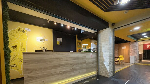 A reception area with a wooden counter, a map on the wall, and a sign indicating directions. - Taipei Inn (Taipei)