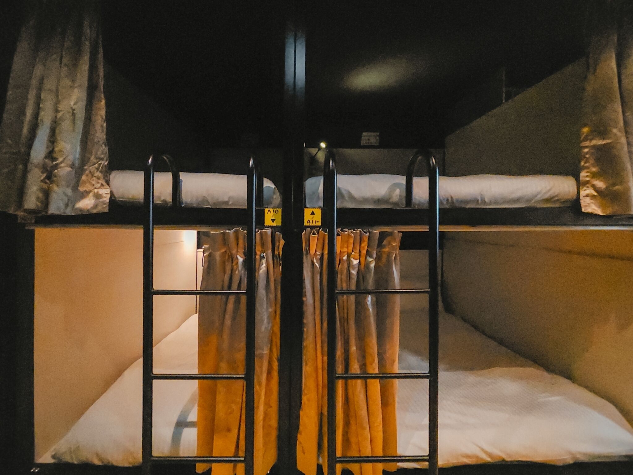 Quarto com beliche, cortinas e uma pequena janela.