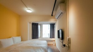 A hotel room with a large bed, a flat-screen TV mounted on the wall, and a window with curtains. - Taipei Inn (Taipei)