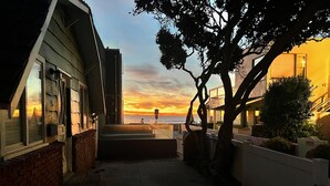 A narrow pathway leading to a building with a view of the sunset over the water.