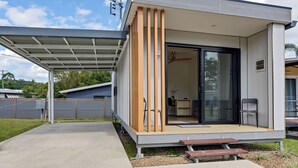 Une maison moderne dotée d’un patio couvert, d’une porte-fenêtre coulissante et d’un petit espace de détente extérieur.