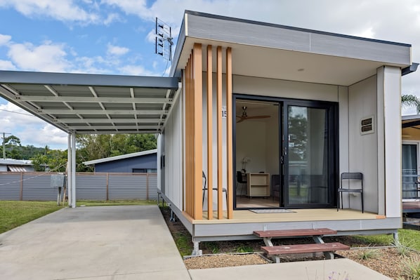 Een modern huis met een overdekte patio, een glazen schuifdeur en een klein zitgedeelte buiten.