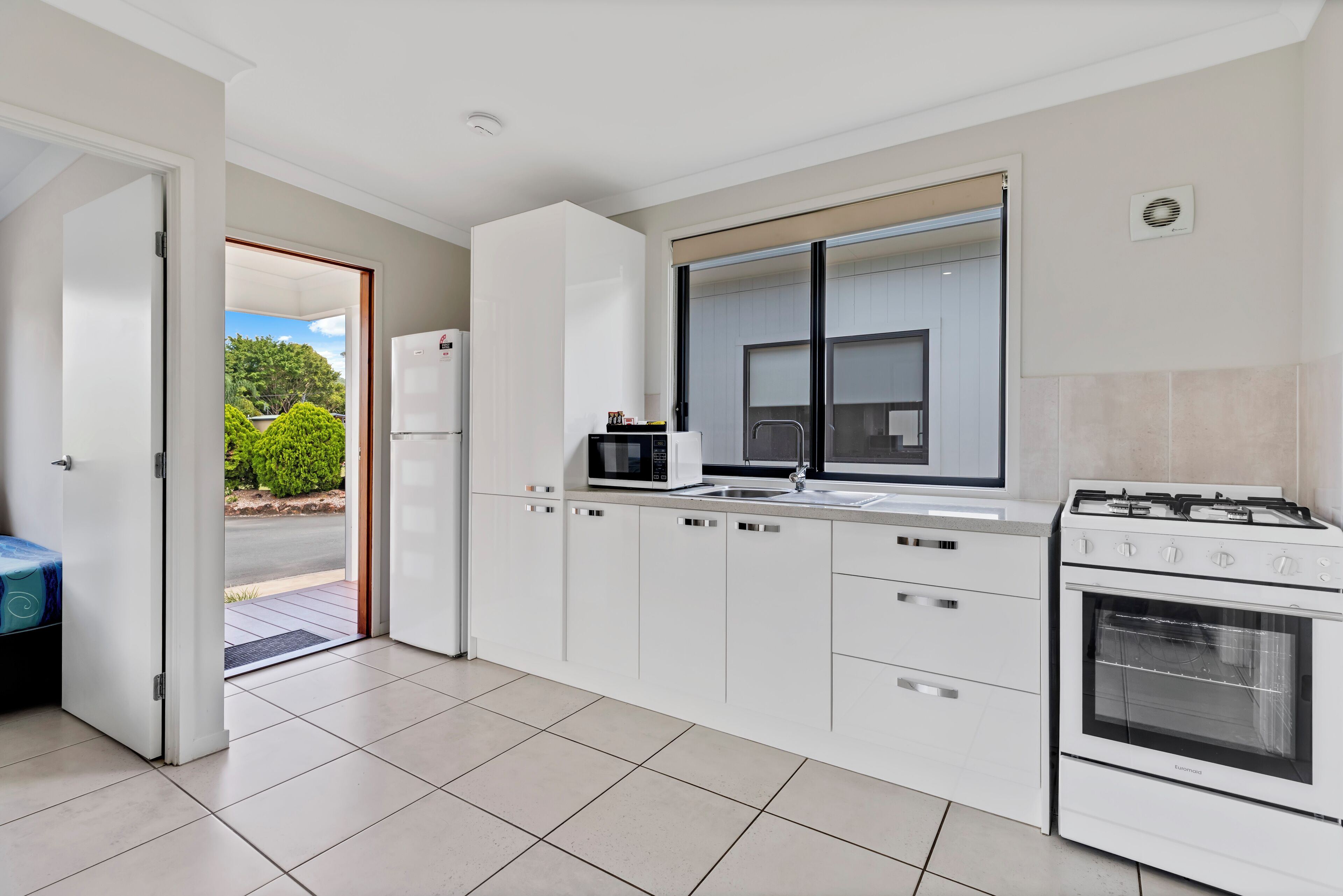 A modern kitchen with white cabinetry, a built-in microwave, a gas stove, and a large window.