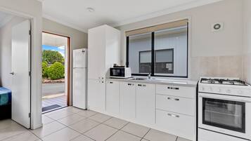 A modern kitchen with white cabinetry, a built-in microwave, a gas stove, and a large window.