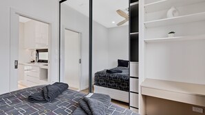 Une chambre à coucher moderne, équipée d’un lit, d’une armoire, d’un bureau et d’un ventilateur de plafond.