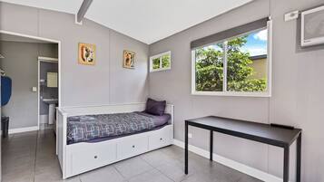 Un dormitorio con cama, ventana, una mesa y obras de arte en la pared.