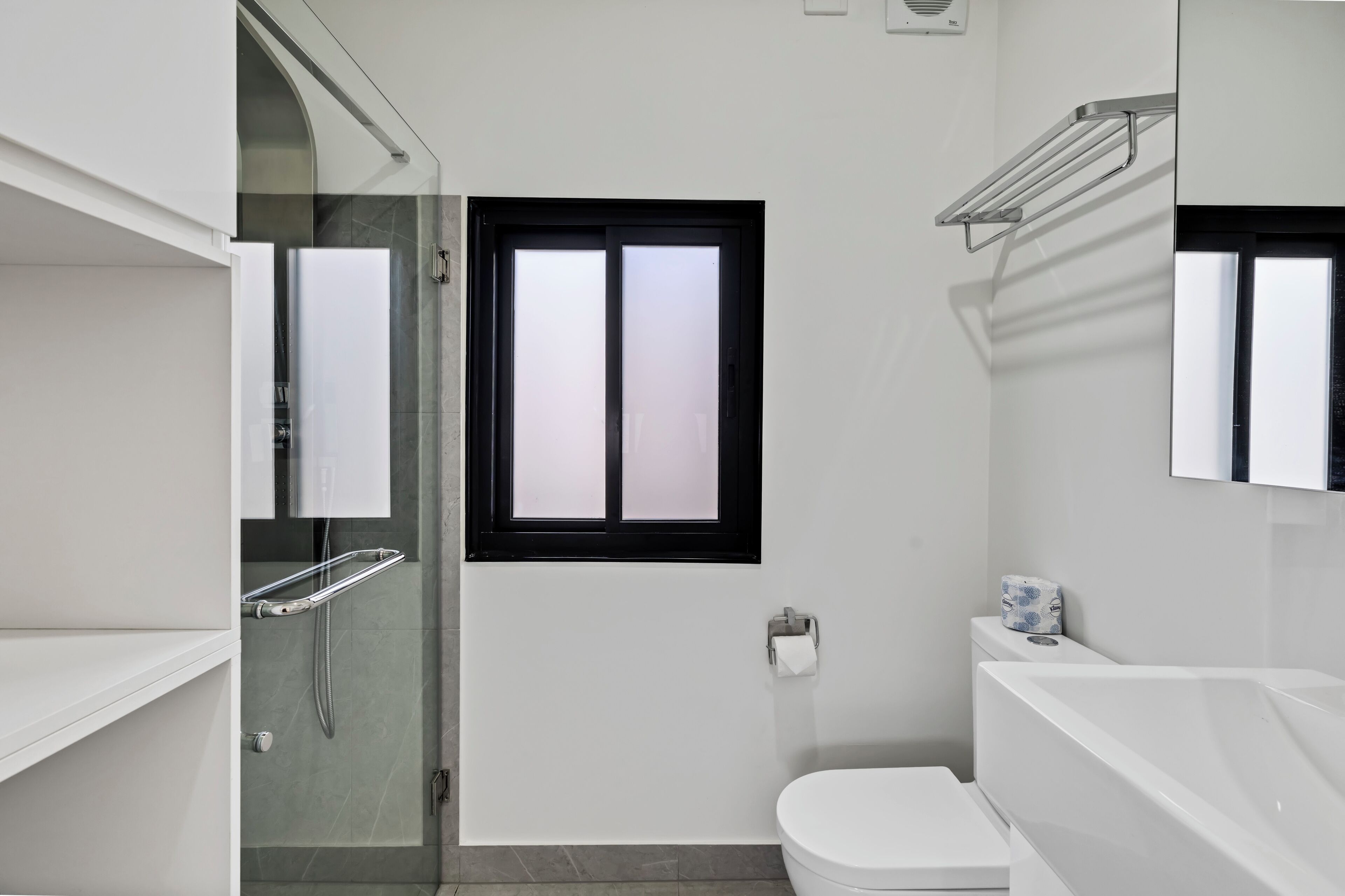 A modern bathroom with a glass shower enclosure, a toilet, and a bathtub.