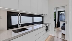 Une cuisine moderne dotée d’une grande fenêtre, de meubles blancs et d’un évier encastré.