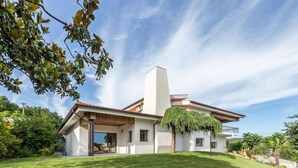 A modern house with a large front lawn, a prominent chimney, and a covered porch area. - 6-bed House - Sleeps 12 - Pool, Bbq, Pool Table (Guimarães)