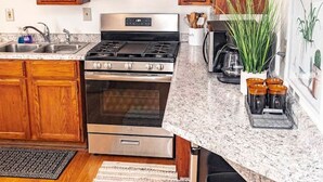 Une cuisine avec des meubles en bois, des appareils en acier inoxydable, un plan de travail en granit et une plante en pot.