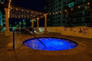Relax by the poolside lounge with a hot tub, surrounded by palm trees and a pergola.