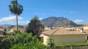 A residential area with terracotta-roofed houses, a palm tree, and a mountain in the background. - Townhouse ALDEA DEL MAR with direct access to the swimming pool (Poblets (els))