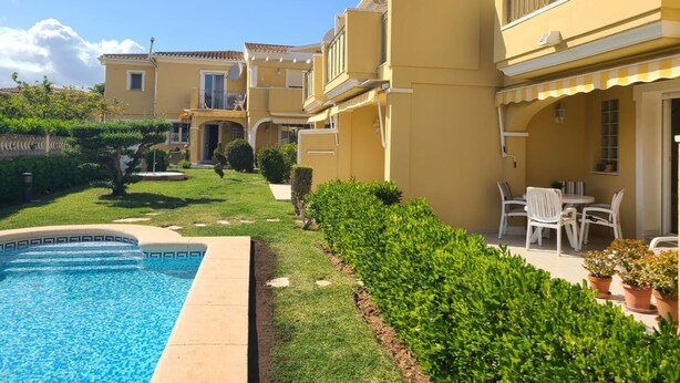 A residential building with a swimming pool, a well-maintained garden, and outdoor seating. - Townhouse ALDEA DEL MAR with direct access to the swimming pool (Poblets (els))