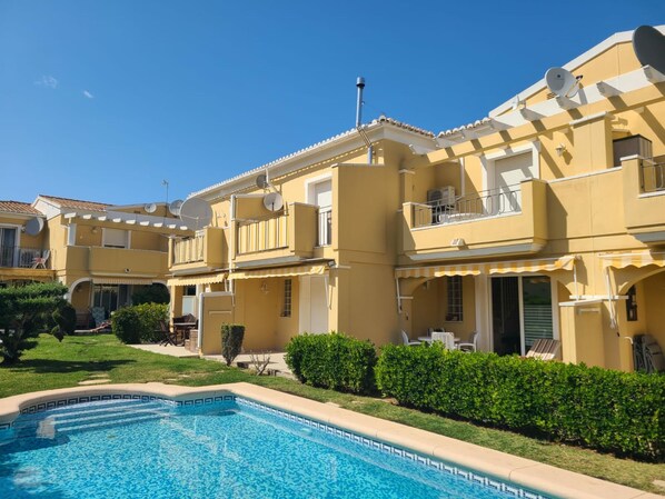 A yellow building with balconies, a swimming pool, and satellite dishes. - Townhouse ALDEA DEL MAR with direct access to the swimming pool (Poblets (els))