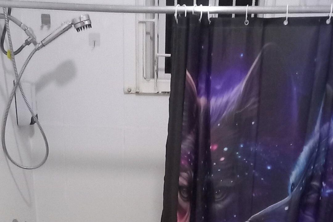 Ein Badezimmer mit Duschvorhang, der ein Weltall-Muster zeigt.