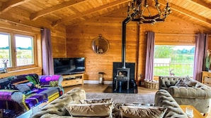 Interior acogedor de una cabaña de madera con televisión, chimenea y asientos cómodos.