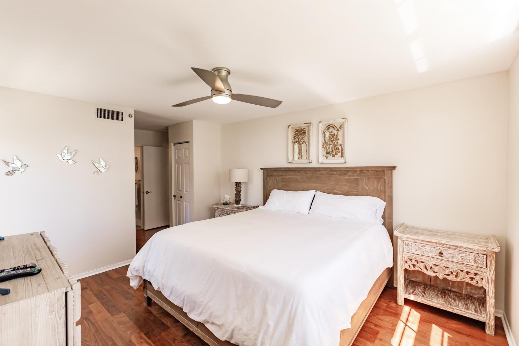 A bedroom with a bed, a ceiling fan, a nightstand, and wall decorations.