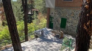 A stone building with a green door, a balcony with a metal railing, and surrounding trees.