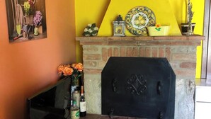Une cheminée avec un manteau en briques, agrémentée de divers objets décoratifs, notamment une assiette, un vase avec des fleurs et une petite statue.