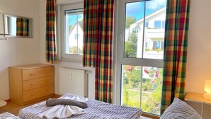 A bedroom with a bed, a dresser, and a window with curtains.