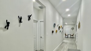 A hallway with white walls, a wooden floor, and a dining area with a table and chairs. - Modern Home In Melbourne (Melbourne)