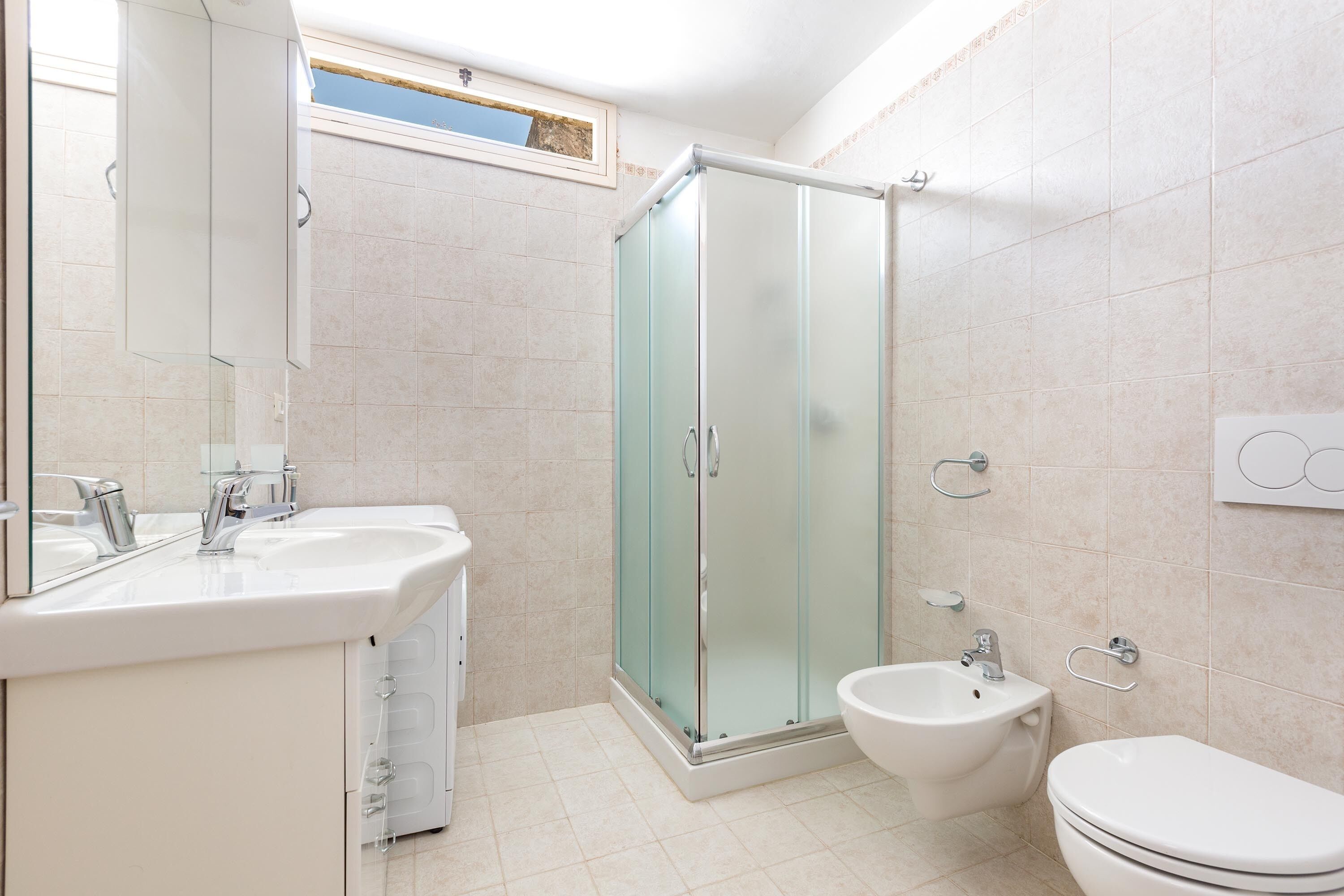 A modern bathroom with a glass shower enclosure, a bidet, and a toilet.