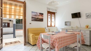 A dining area with a checkered tablecloth, a yellow sofa, and a painting of a lighthouse. - 2808 Case al Tacco - Appartamento Terra by Barbarhouse (Castrignano del Capo)