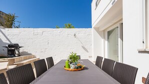 Ein Essbereich mit Tisch, Stühlen, einem Blumentopf und einem Grill.