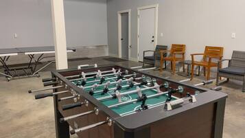 A room with a foosball table, two doors, and four chairs.
