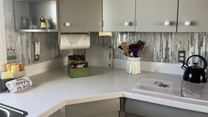 Een keuken met een wit aanrecht, een waterkoker, een mand met lekkernijen en een bordje met de tekst 'Happy PLACE'.