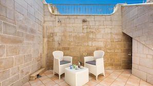 A small outdoor patio with two wicker chairs and a round table, set against a stone wall with a metal railing above. - 2516 Villa Marea - Appartamento Bassamarea by Barbarhouse (Salve)