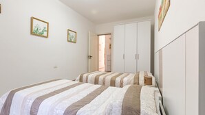 A bedroom with two beds, a wardrobe, and two framed pictures on the wall. - 2516 Villa Marea - Appartamento Bassamarea by Barbarhouse (Salve)