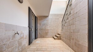 A narrow hallway with stone flooring, a metal handrail, and a door on the left. - 2516 Villa Marea - Appartamento Bassamarea by Barbarhouse (Salve)