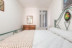 Um quarto com uma cama, cômoda, espelho e porta que dá para um banheiro.