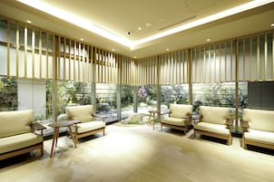 Un intérieur moderne avec deux canapés et de petites tables, de grandes fenêtres et une vue sur un jardin.