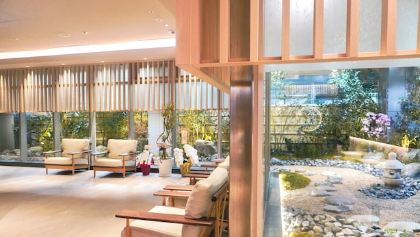 A modern interior with seating areas and a view of an outdoor garden.