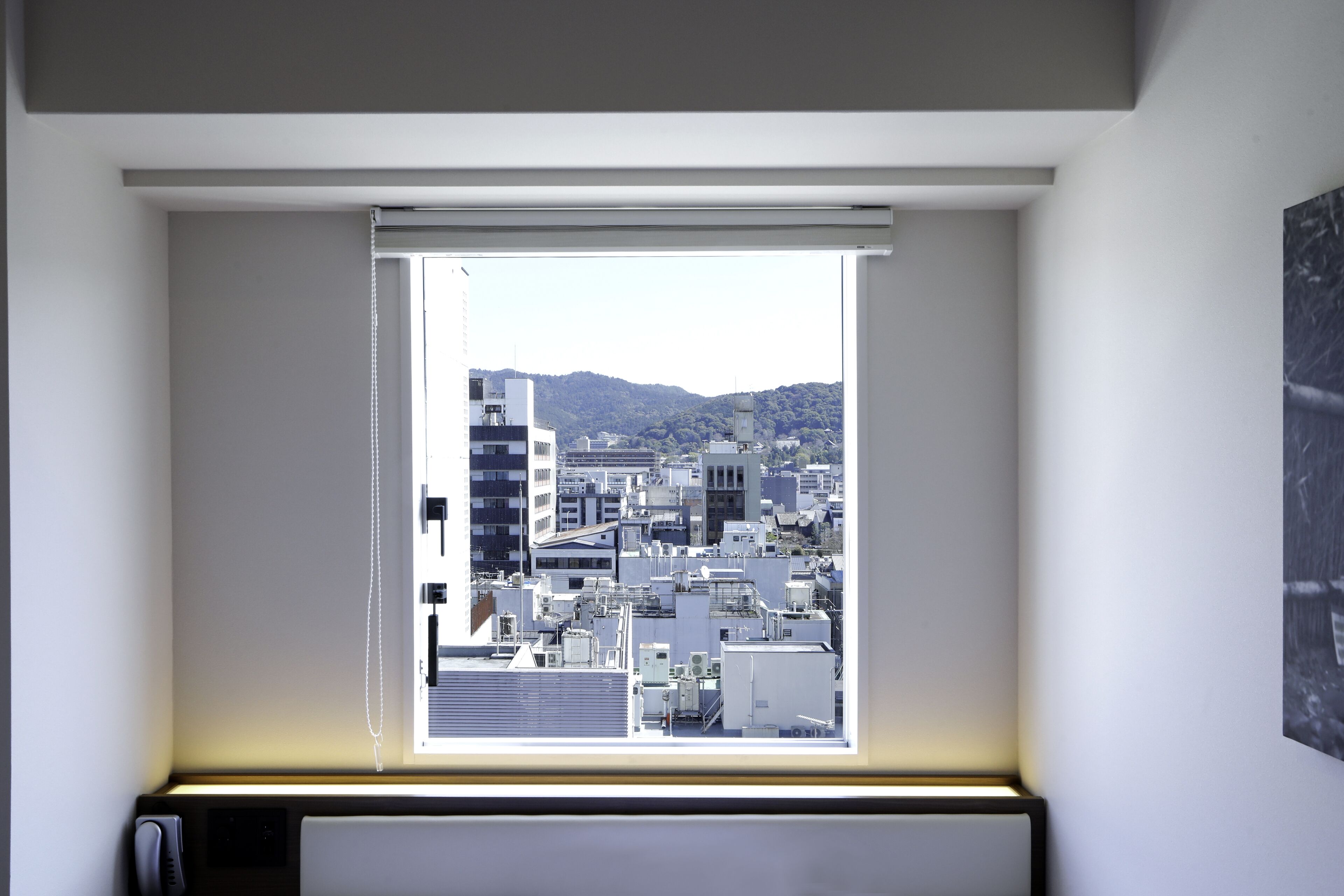 A room with a window overlooking a cityscape, including buildings and a mountain.