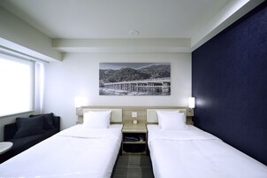 A hotel room with two beds, a sofa, a small table, and a wall-mounted picture.