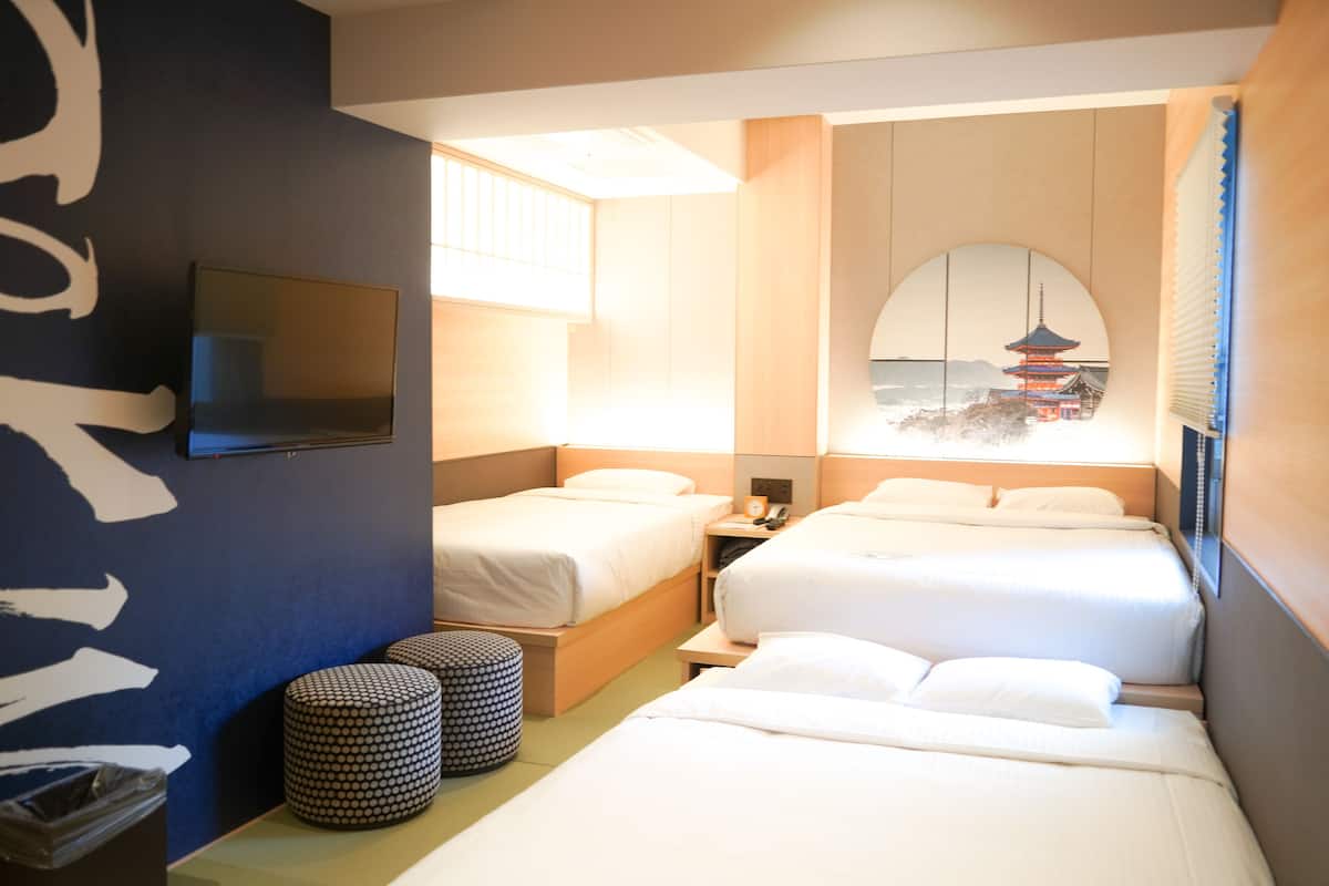 A hotel room with two beds, a TV, a mirror, and a view of a pagoda.