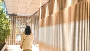 A corridor with a modern design, featuring a wooden slat wall and recessed ceiling lights.