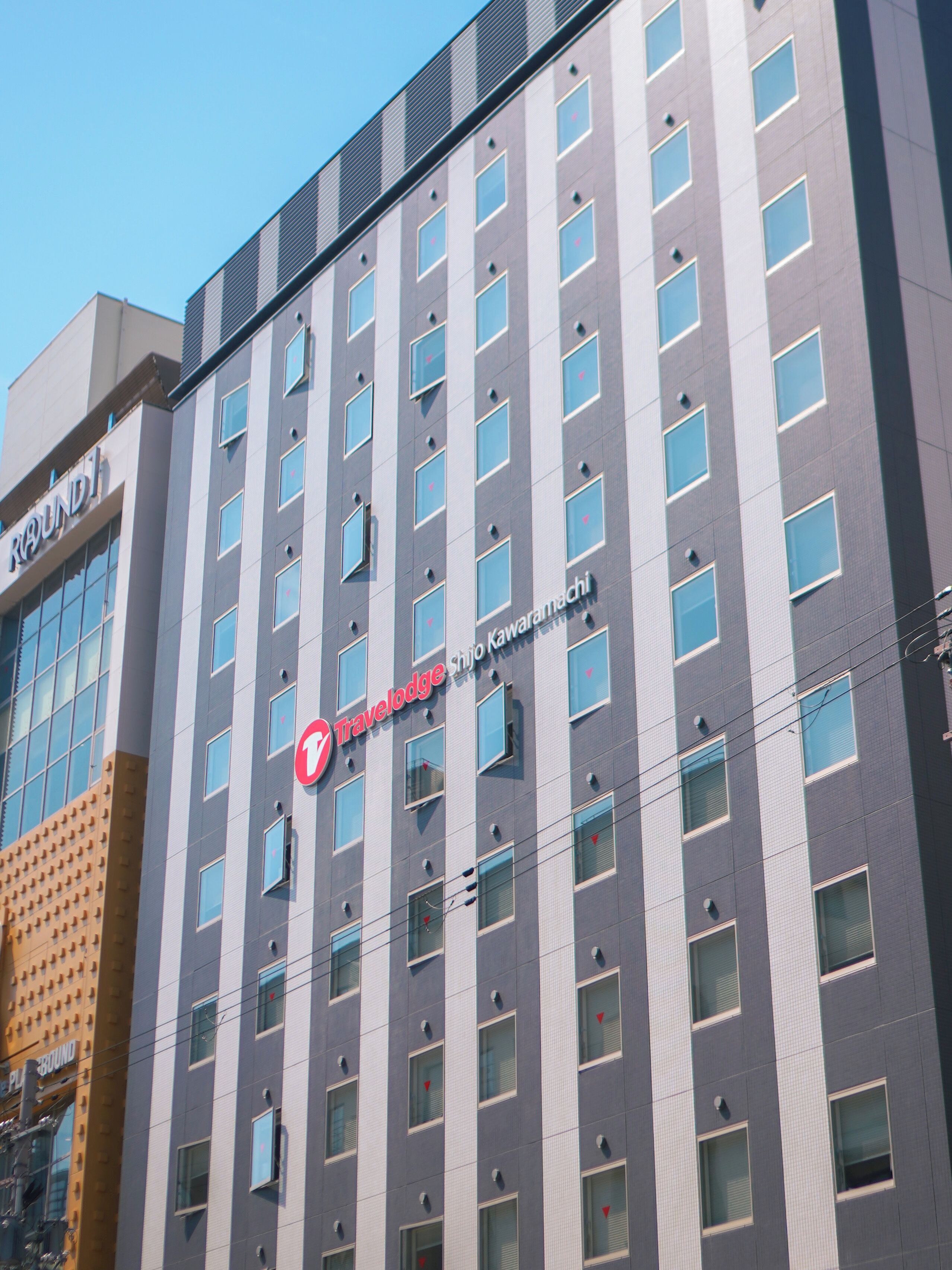 Un bâtiment moderne arborant le logo de la chaîne Travelodge, doté de nombreuses fenêtres et d’une façade plane.