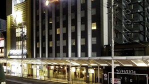A multi-story hotel with a modern facade, illuminated signage, and a covered entrance area.