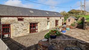 A stone building with multiple windows and a paved courtyard. - Great Meadow Barn (Newquay)