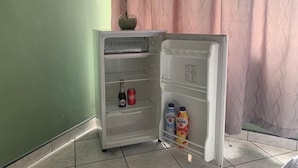 Ein kleiner, offener Kühlschrank mit einer Coca-Cola Flasche und zwei Gloria Flaschen.