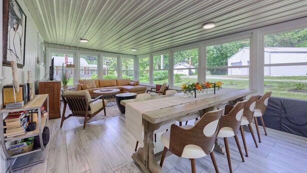 A covered patio with a dining area, seating, and a view of the outdoors. - The Boathouse on Moon Lake (Ashland)