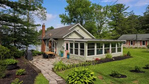 A house with a covered patio, a brick chimney, and a well-maintained lawn. - The Boathouse on Moon Lake (Ashland)