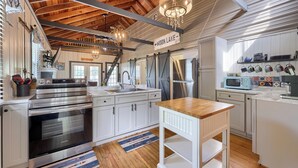 A modern kitchen with stainless steel appliances, wooden beams, and a chandelier. - The Boathouse on Moon Lake (Ashland)