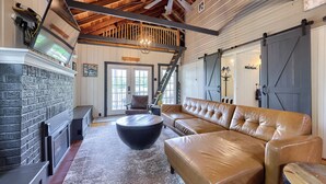 A spacious living room with a large leather sofa, a fireplace, and a ceiling fan. - The Boathouse on Moon Lake (Ashland)